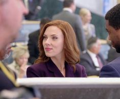 two men and a woman sitting at a table talking to each other