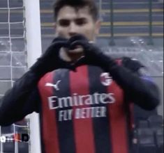 a soccer player standing in front of a goalie net with his hands on his face