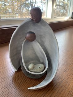 a clay sculpture sitting on top of a wooden table next to a window sill