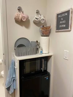 a microwave oven sitting on top of a white cabinet next to a wall mounted dishwasher