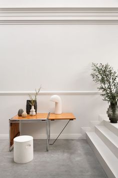 a table with two vases sitting on top of it next to some white steps