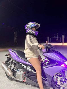 a woman sitting on top of a purple motorcycle