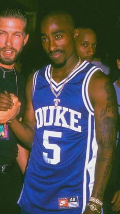 two men standing next to each other in front of a group of people at a basketball game