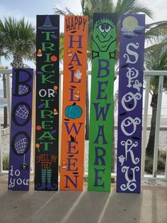 colorful wooden signs with happy halloween written on them in front of the ocean and palm trees