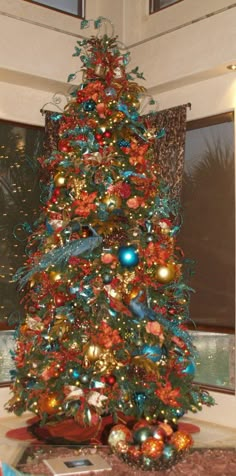 a brightly colored christmas tree in a living room with red and blue ornaments on it