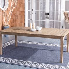 a wooden table sitting on top of a blue rug in front of a white door