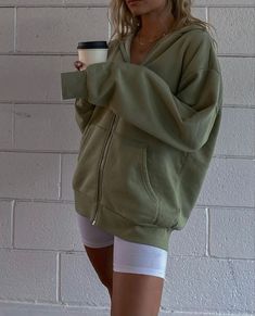 a woman is holding a coffee cup and wearing shorts