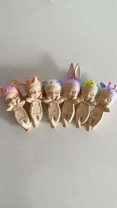 five wooden toy figurines of babies with bunny ears and tails, all in different colors