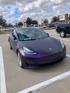 a purple tesla parked in a parking lot