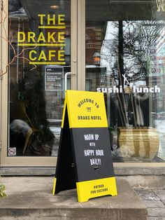 a yellow sign sitting on the sidewalk in front of a storefront with an open door