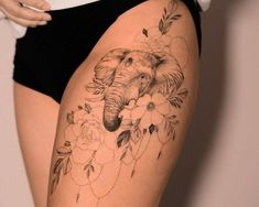 an elephant and flowers tattoo on the side of a woman's thigh is shown