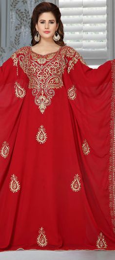 a woman wearing a red gown with gold embroidery on the shoulders and sleeves, standing in front of a window