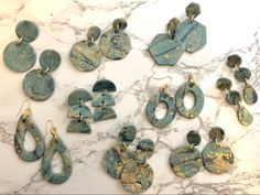 many different pieces of blue and gold jewelry on a marble counter top, including earrings