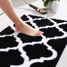 a person standing on top of a black and white rug next to a potted plant