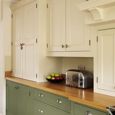 a kitchen with white cabinets and green cupboards on the counter top, along with a toaster oven