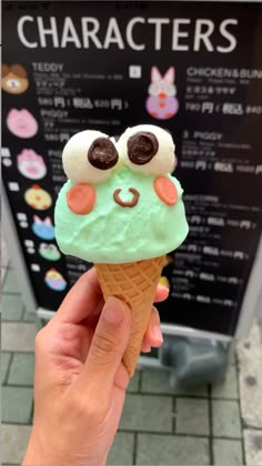 a hand holding an ice cream cone with green frosting and chocolate googly eyes