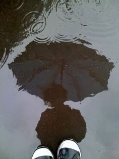 a person standing in front of a puddle with their feet on the ground next to an umbrella