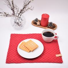 a plate with waffles on it next to a cup of coffee and a candle