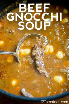 a ladle full of soup with meat and vegetables in it on a wooden table