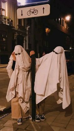 two people dressed in white standing next to a street sign