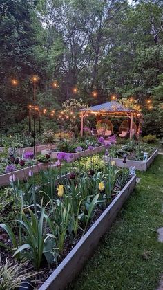 a garden filled with lots of plants and flowers next to a gazebo surrounded by trees