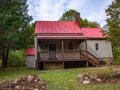 a small house with a red roof in the woods