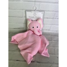 a pink knitted elephant wrapped in a pink blanket on a white brick wall background