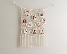 a white wall hanging with pictures and pins attached to the side of it on a string