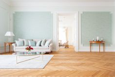 a living room with light blue walls and wood flooring on the wooden floor, along with a glass coffee table