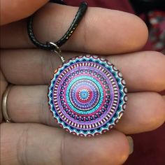 a person is holding a colorful pendant in their hand and it looks like the inside of a circle