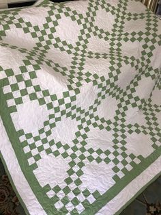 a green and white quilt on a bed