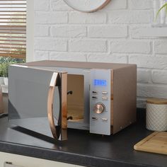 a microwave oven sitting on top of a counter next to a cutting board and potted plant