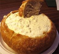 a bread bowl filled with cream cheese on top of a white plate