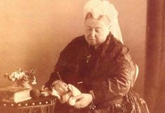 an old photo of a woman sitting at a table with a basket and pen in her hand