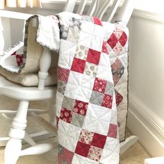 a white rocking chair with a red and gray quilted blanket on top of it