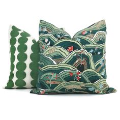 two pillows with green and white designs on them, one in the shape of mountains