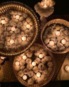 candles are lit in the middle of two pie pans filled with flowers and leaves