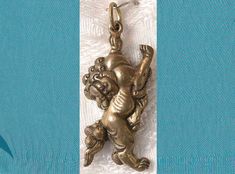 a gold charm with an image of a monkey on it's back hanging from a white ribbon