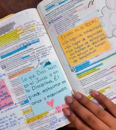 an open bible with sticky notes attached to the pages, and someone's hand holding it