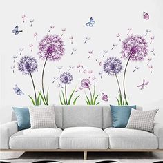 a living room filled with furniture and lots of purple flowers on the wall next to a white couch