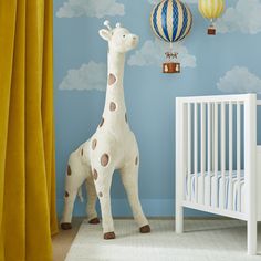 a stuffed giraffe standing next to a crib