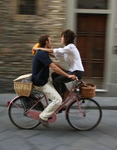 two people riding on the back of a bike