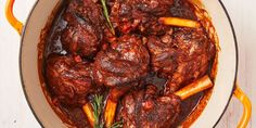 a pot filled with meat and carrots on top of a table