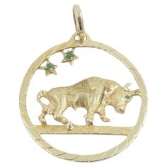 A unique 14k gold vintage charm Taurus pendant. The pendant is open-work, with a walking bull figure placed in the center. The Taurus is crafted of textured gold, with an eye accented with a green gemstone. Two more similar gems four-prong set above the bull in the star design. The scene is framed in a polished and grooved circular frame. This beautiful Zodiac jewelry piece was skillfully created with true artistry. About Astrological jewelry Astrological jewelry has found its niche in the world Astrological Jewelry, Taurus Pendant, Victorian Pendant Necklace, Zodiac Pendant Necklace, Gold Horns, Circular Frame, Crescent Necklace, The Bull, Gold Nugget