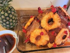 a pineapple upside down cake on a tray next to a bowl of syrup and a pineapple