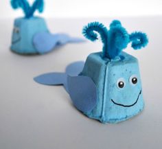 two little blue sea creatures made out of toilet paper with eyes and ears, sitting on a white surface