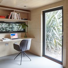 a laptop computer sitting on top of a white desk next to a book shelf filled with books