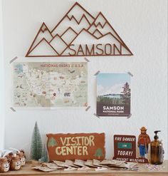 a wooden table topped with lots of items next to a wall covered in signs and pictures