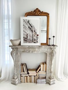 an ornate fireplace mantel with books stacked on it and a framed photograph in the corner