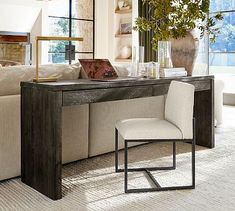 a living room with a couch, table and chair next to a vase on the floor